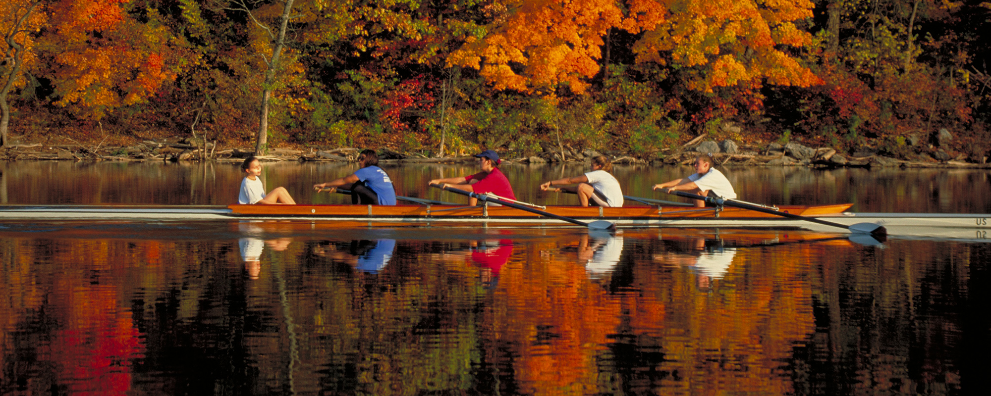 Four person rowing shell on a lake in fall