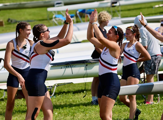 Girl's novice rowers high fiving after race