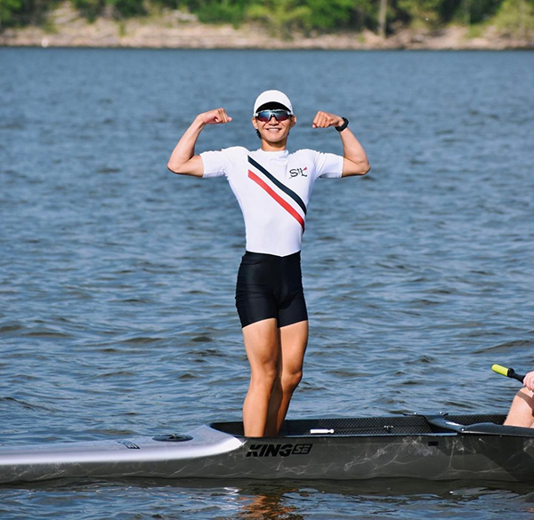 Varsity boys coxwain flexing on boat